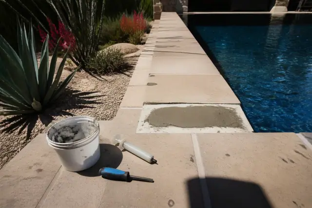 Technician repairing loose coping stones on a rectangular pool deck in Scottsdale, AZ.