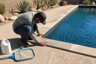 Technician inspecting pool coping by a rectangular backyard pool in Phoenix, AZ.