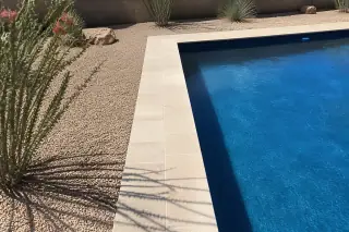 Newly installed stone coping and clean grout lines on a rectangular pool deck in Phoenix, AZ.