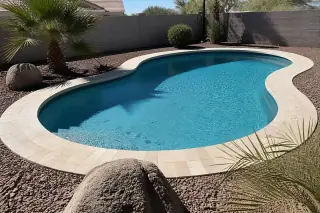 Fresh plaster and new stone coping on a residential swimming pool in Phoenix, AZ, surrounded by volcanic rock landscaping.