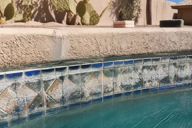 Pool tile cleaning in progress on a residential pool in Avondale, AZ, showing mineral removal near desert landscaping.