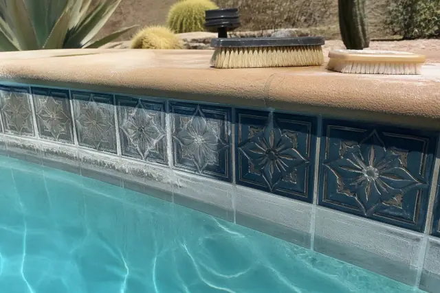 Close-up of pool tile cleaning showing mineral deposit removal in a Scottsdale, AZ backyard.