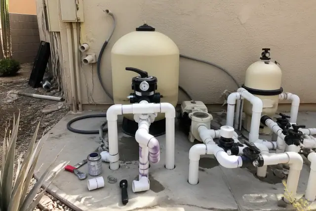 Pool equipment pad with filtration tanks and PVC plumbing repairs at a residential jobsite in Phoenix, AZ.