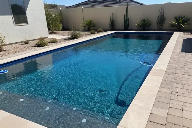 Residential rectangular swimming pool with desert landscaping and stone deck in a backyard in Phoenix, AZ.