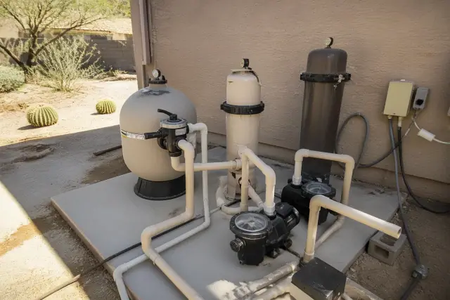 Pool equipment pad in Phoenix, AZ featuring sand, cartridge, and DE pool filters with plumbing and booster pumps.