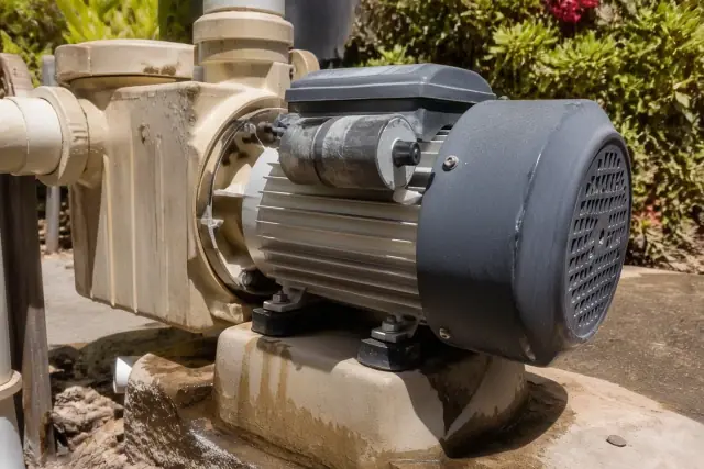 Pool circulation motor casing on a high-pressure pump in Phoenix, AZ, with desert landscaping in the background.