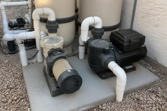 Single-speed and variable-speed pool pumps on a concrete pad at a home in Phoenix, AZ.