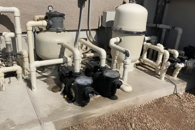 Variable-speed pool pumps and filtration equipment on a concrete slab at a jobsite in Phoenix, AZ.