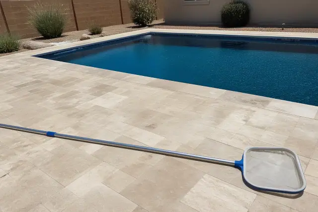 Skimmer net and telescope pole on a pool deck at a residential backyard in Avondale, AZ.