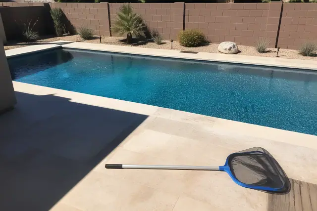 A telescoping pole and leaf net resting on a pool deck during weekly pool service in a backyard in Phoenix, AZ.