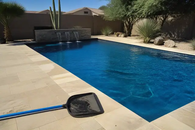 Skimming net on the deck of a backyard pool during a weekly service visit in Mesa, AZ.