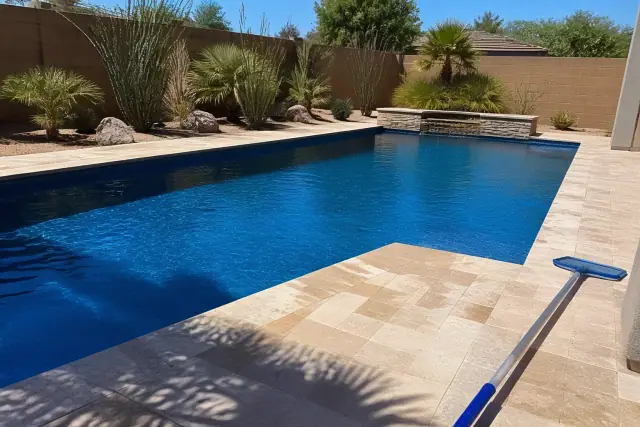 A clear rectangular swimming pool with a telescopic pole on the deck at a home in Chandler, AZ.