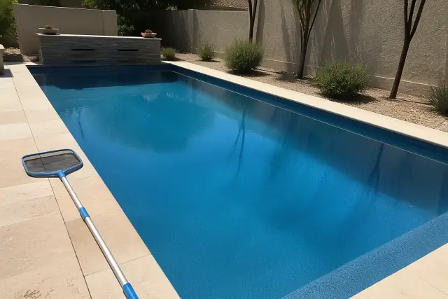 Crystal clear water in a residential swimming pool after cleaning in Phoenix, AZ, with a pool net on the deck.