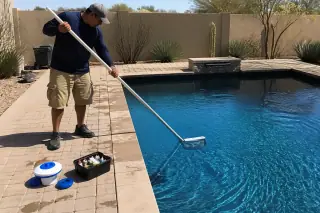 Technician skimming a rectangular pool and testing water chemistry in a Phoenix, AZ backyard.