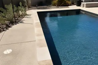 Rectangular swimming pool with clean stone coping and desert landscaping in Phoenix, AZ.