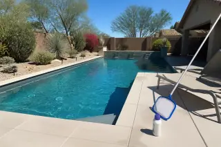 Sparkling pool after a weekly maintenance service in Phoenix, AZ, with a skimmer pole and chemicals on the deck.