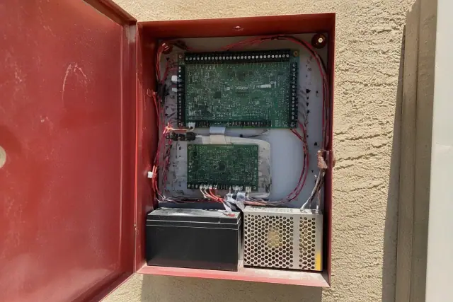 Open fire alarm control panel cabinet with circuit boards on a stucco wall in Phoenix, AZ.