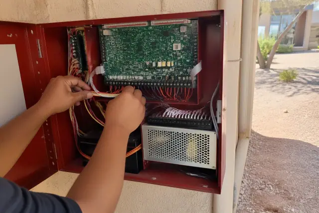 Technician wiring a fire alarm control panel cabinet during an installation in Phoenix, AZ.
