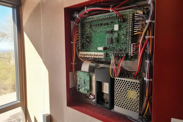 Technician wiring complex circuits inside a fire alarm control panel cabinet in Phoenix, AZ.