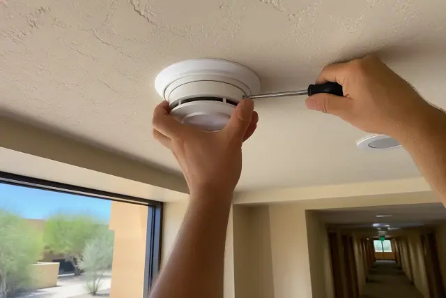 Smoke detector mounted on a ceiling near a bedroom and hallway in a Phoenix, AZ home.