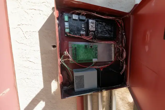 Technician wiring a fire alarm communicator inside a control panel cabinet in Phoenix, AZ.