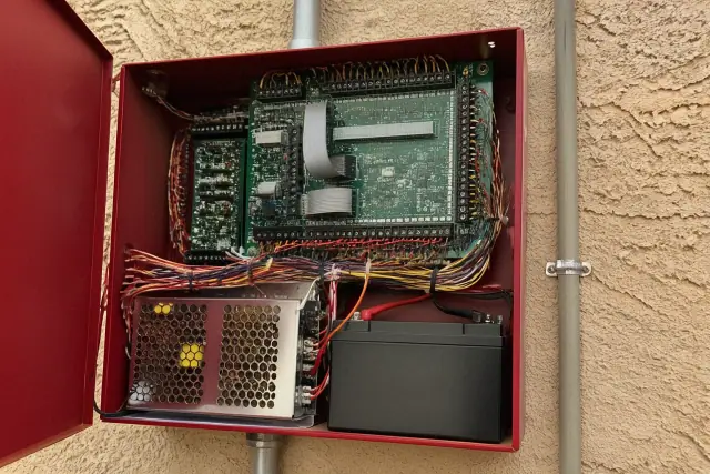 Technician wiring a fire alarm control panel inside a building in Glendale, AZ.