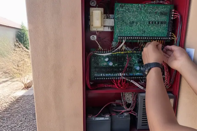 Technician wiring a commercial fire alarm control panel in Phoenix, AZ.