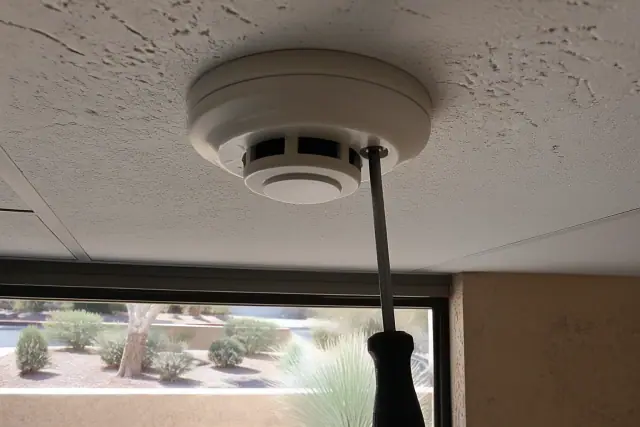 Technician mounting a smoke detection sensor to a commercial ceiling junction box in Phoenix, AZ.