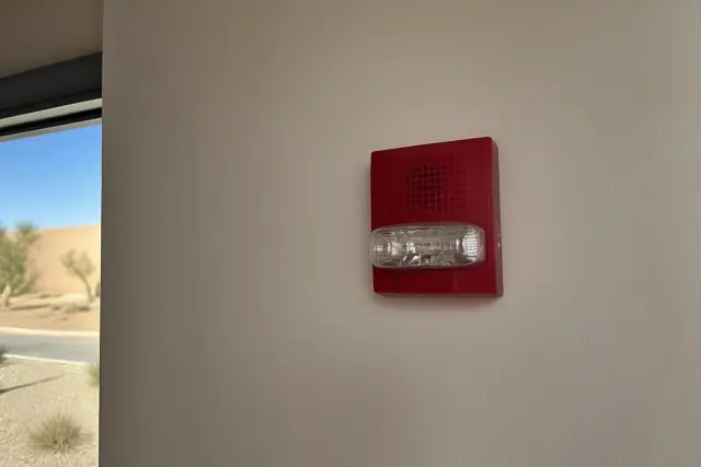 Fire alarm horn-strobe device installed on a stucco wall at a project site in Phoenix, AZ.
