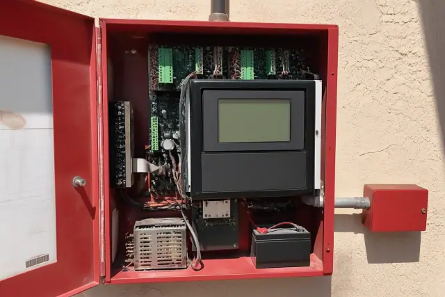 Fire alarm control panel installed on a stucco wall at a job site in Phoenix, AZ.