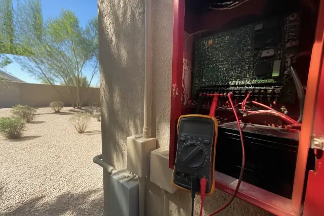 Technician using a multimeter to test a fire alarm system at a building in Goodyear, AZ.