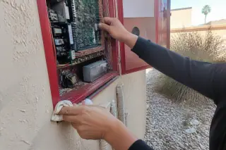 Technician organizing multicolored wiring inside a fire alarm control panel cabinet at a Phoenix, AZ jobsite.