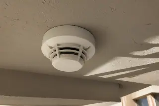 Smoke detection sensor mounted to a ceiling junction box at a commercial worksite in Phoenix, AZ.