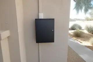 Closed fire alarm control panel cabinet mounted on a stucco wall at a Phoenix, AZ worksite.