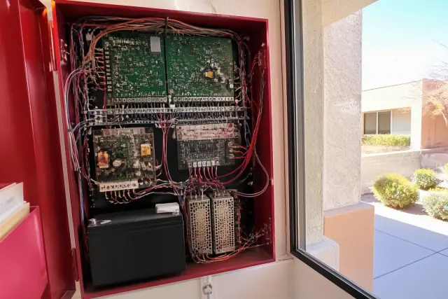 Interior of a wall-mounted fire alarm control panel with multicolored wiring in an Avondale, AZ building.