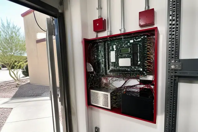 Open fire alarm control panel with neatly wired circuits and power supply at a retail property in Peoria, AZ.