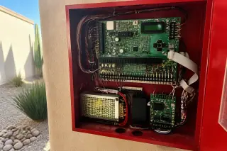 Internal view of a fire alarm control panel with wired circuit boards at a Phoenix, AZ construction site.
