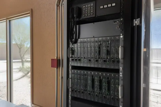 Technician inspecting fire alarm panels and voice evacuation systems inside a server rack in Phoenix, AZ.