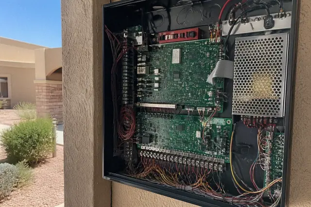 Fire alarm control panel with visible circuits mounted on a stucco wall at a jobsite in Goodyear, AZ.