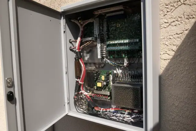 Technician wiring a fire alarm control panel inside a building in Mesa, AZ.