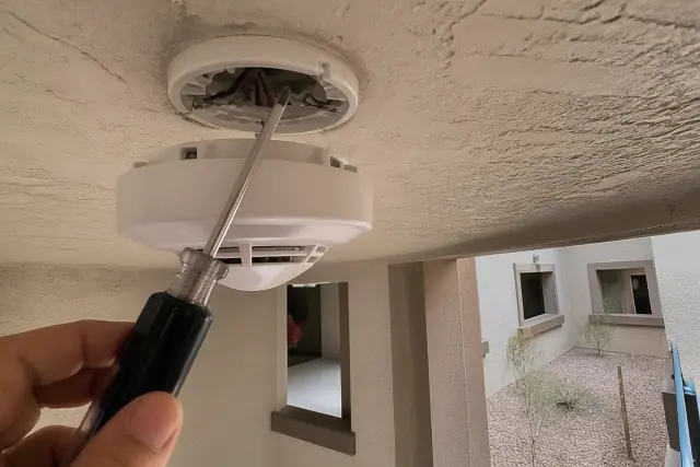 Technician installing a smoke detector on a commercial ceiling in Avondale, AZ.