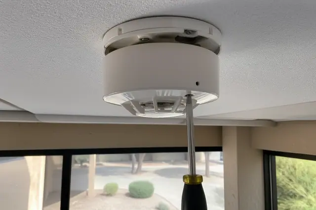 Technician mounting a smoke detection sensor to a commercial ceiling junction box in Tempe, AZ.