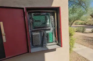 Technician hands working on organized wiring inside a fire alarm control panel at a Phoenix, AZ worksite.