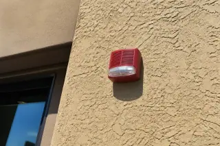 Wall-mounted fire alarm horn-strobe on a dry-stacked masonry wall at a construction site in Phoenix, AZ.