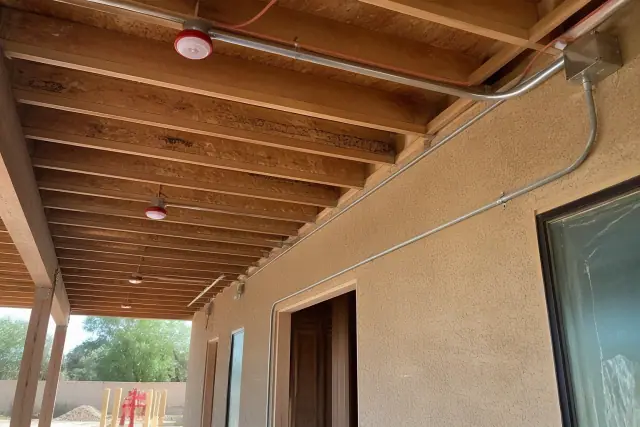 Exposed electrical conduits and fire-rated cabling on an unfinished ceiling at a job site in Phoenix, AZ.