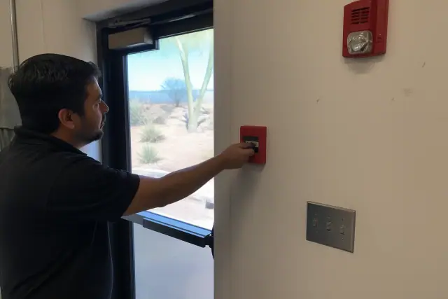 Technician testing a manual fire alarm pull station during a system inspection in Phoenix, AZ.