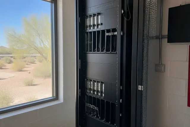 Technician inspecting a voice evacuation amplifier rack in a commercial utility room in Phoenix, AZ.