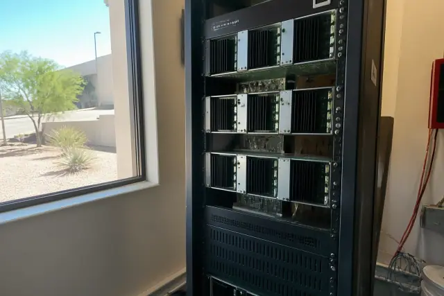Technician inspecting modular amplifier cards in a fire alarm voice evacuation system rack in Mesa, AZ.