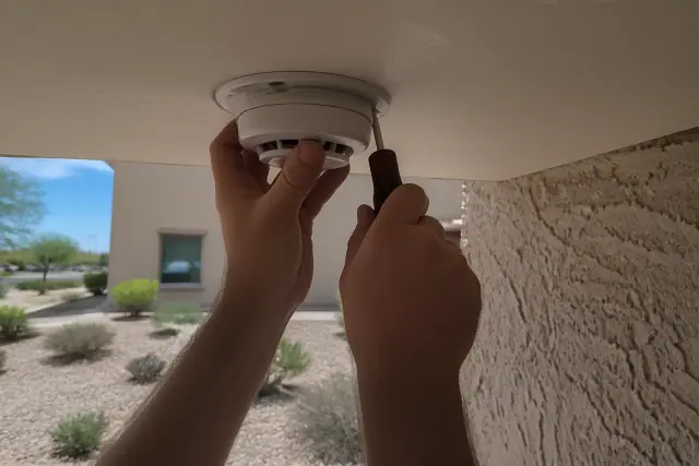 A technician installs a smoke detector on a ceiling junction box at a jobsite in Phoenix, AZ.