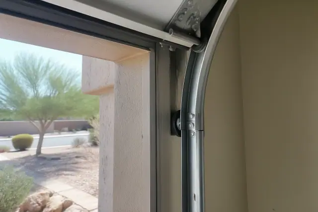Heavy-duty garage door rollers installed in tracks on a sun-bleached stucco home in Phoenix, AZ.